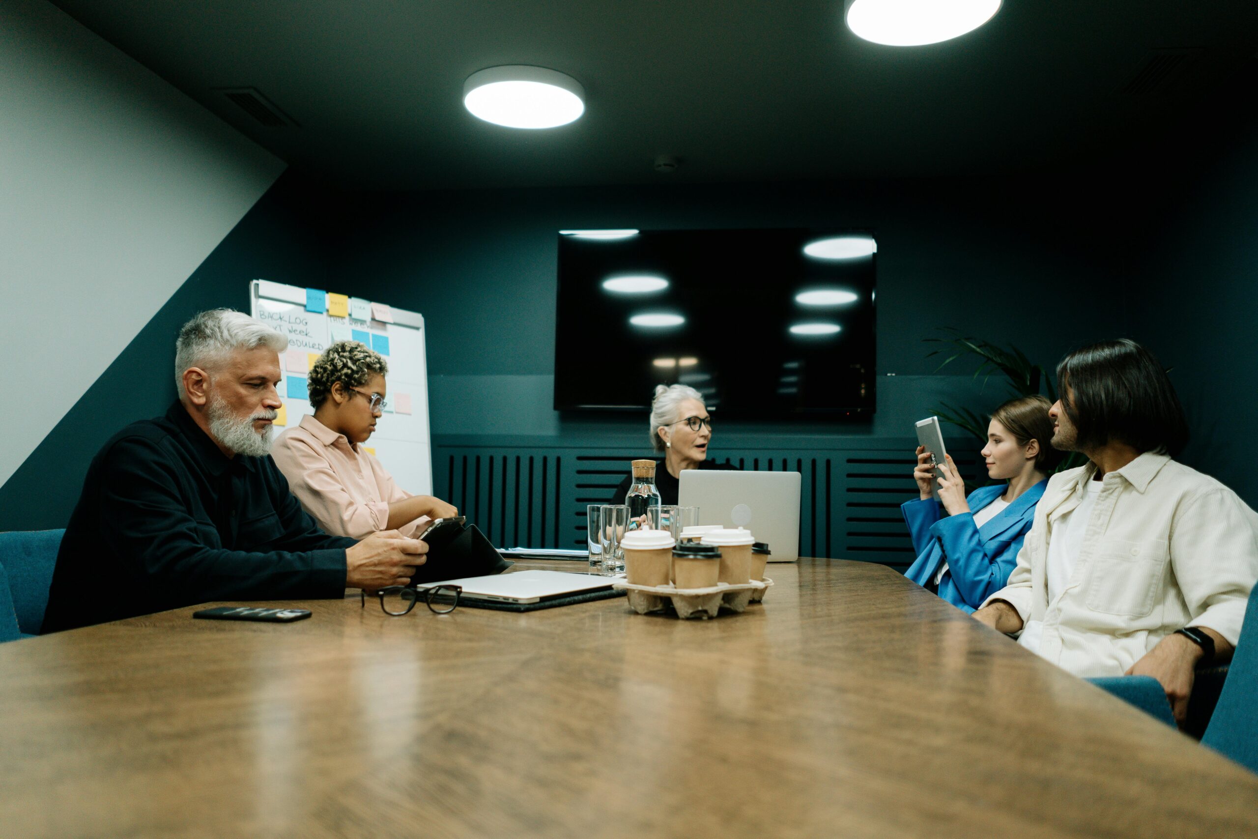 A group of people of different ages sitting together around a boardroom table